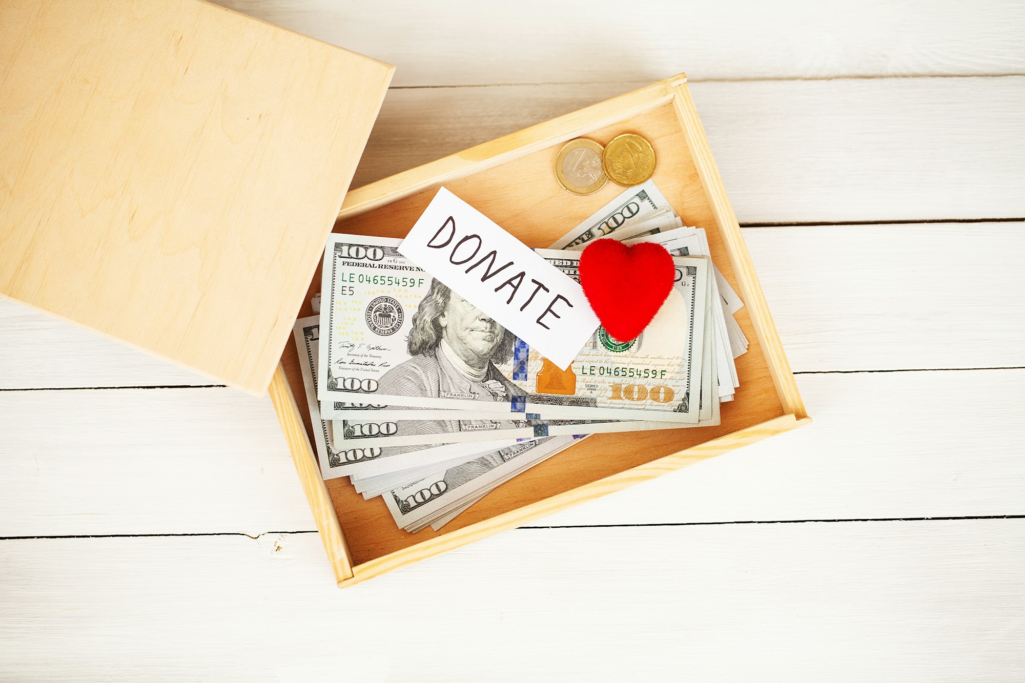 Donate conception. Box with money on white wood background